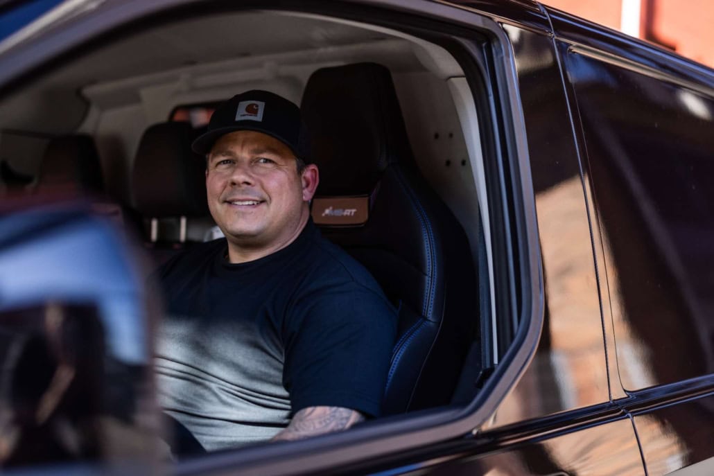 Glad og smilende låsesmed i firmabil